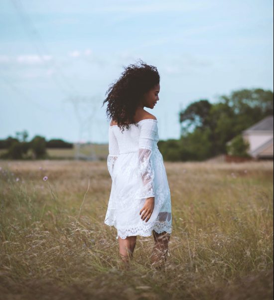 Photo by Ashley Byrd girl in white dress standing on green grass field during daytime
